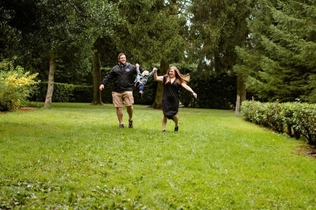 Families Portfolio - a mum and dad swing their little boy in the air between them