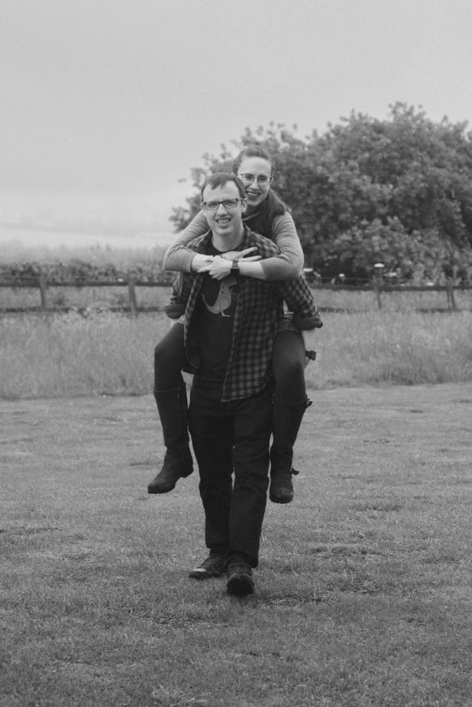 Engagements portfolio - a couple in a field, she is having a Piggy Back B&W image