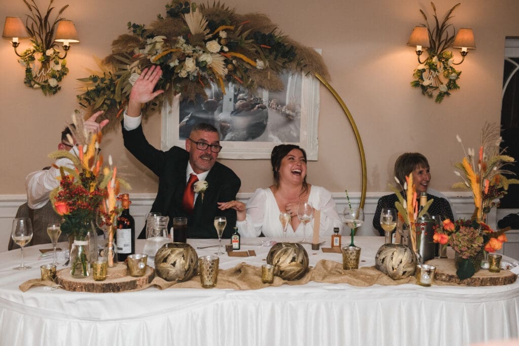 Newly married couple cheering at the top table during the wedding breakfast