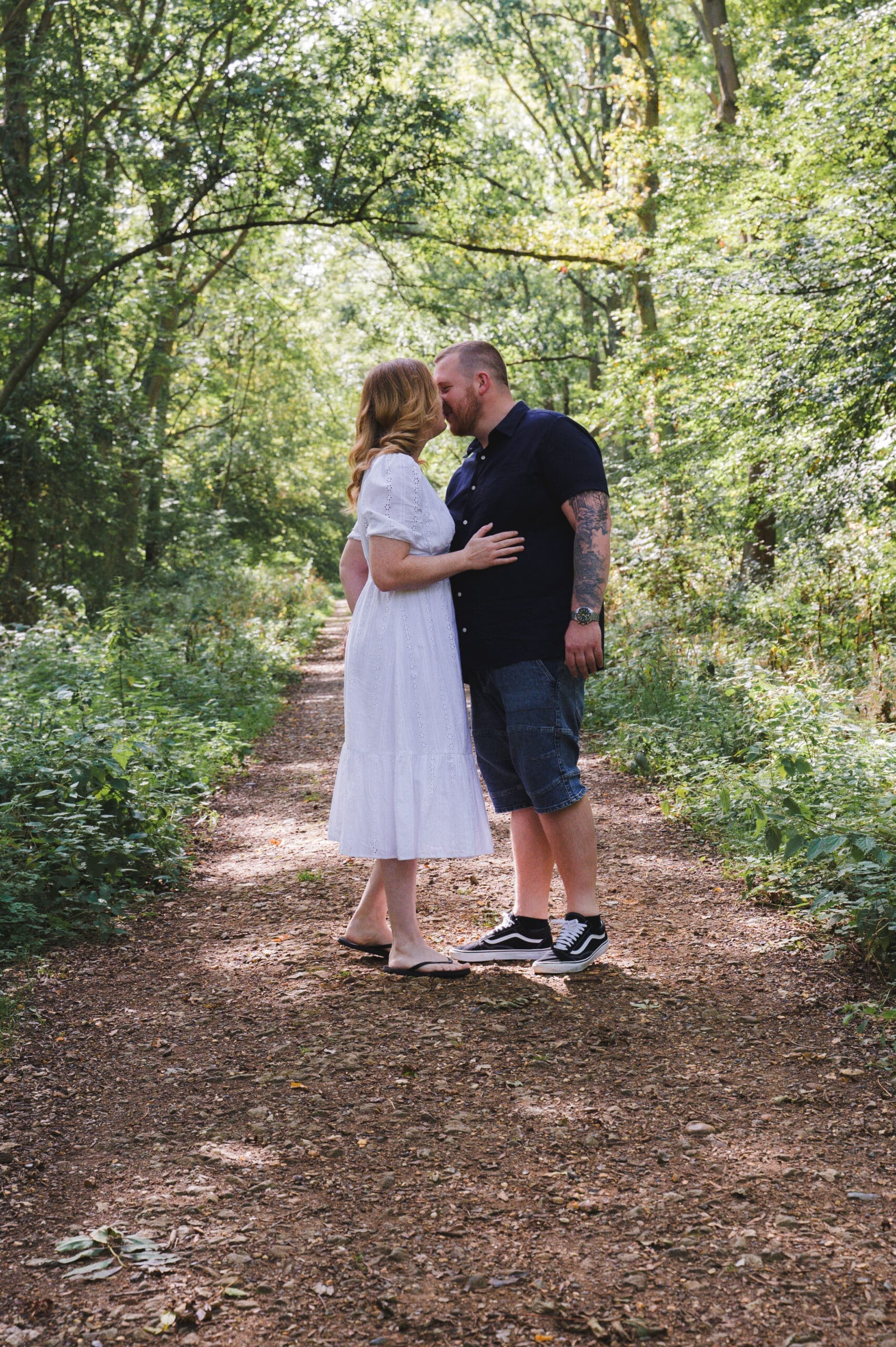 A couple kissing under the shade of woodland trees